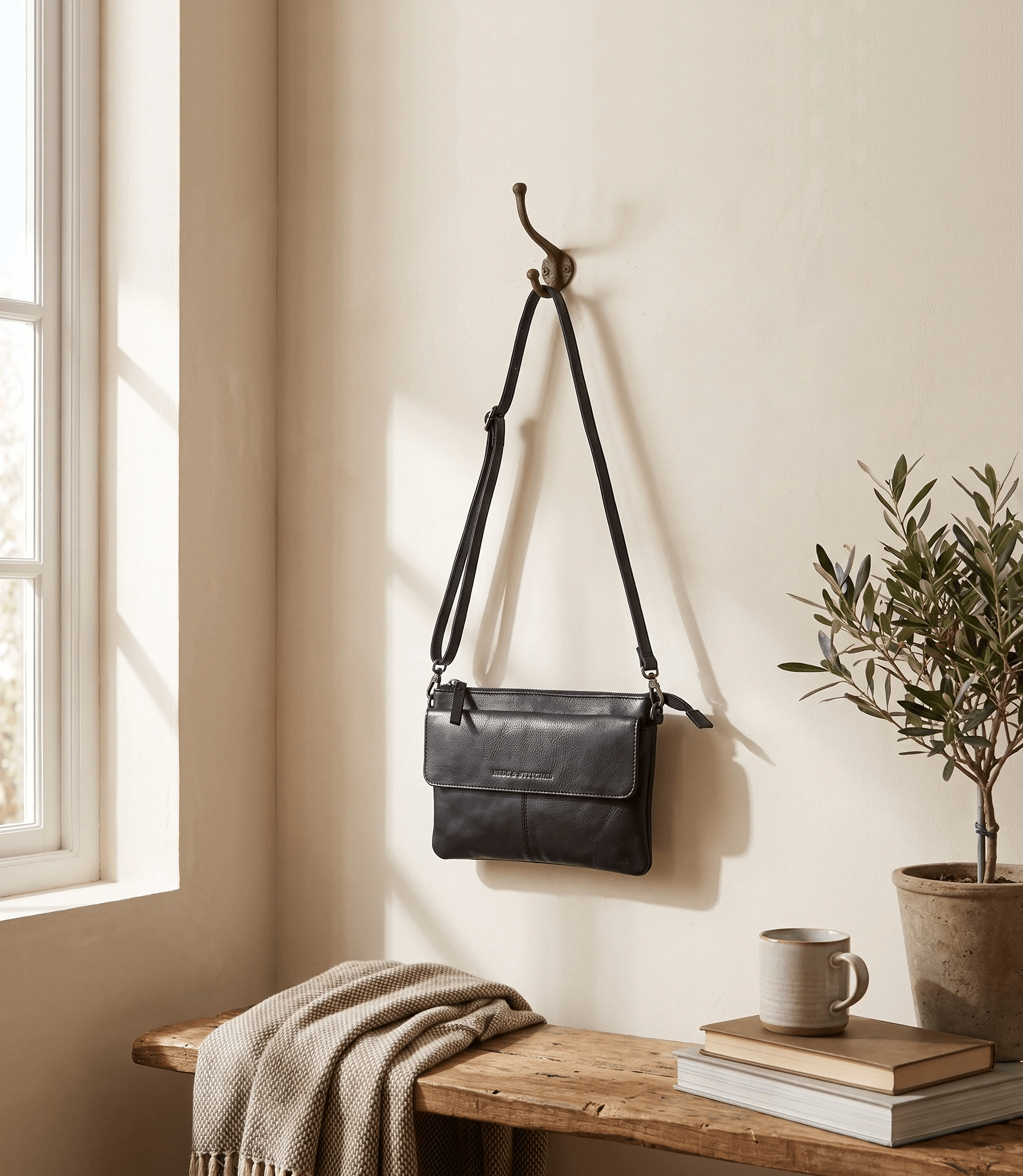 Zwarte Hide & Stitches-schoudertas op geloofwaardige schaal in een licht interieur