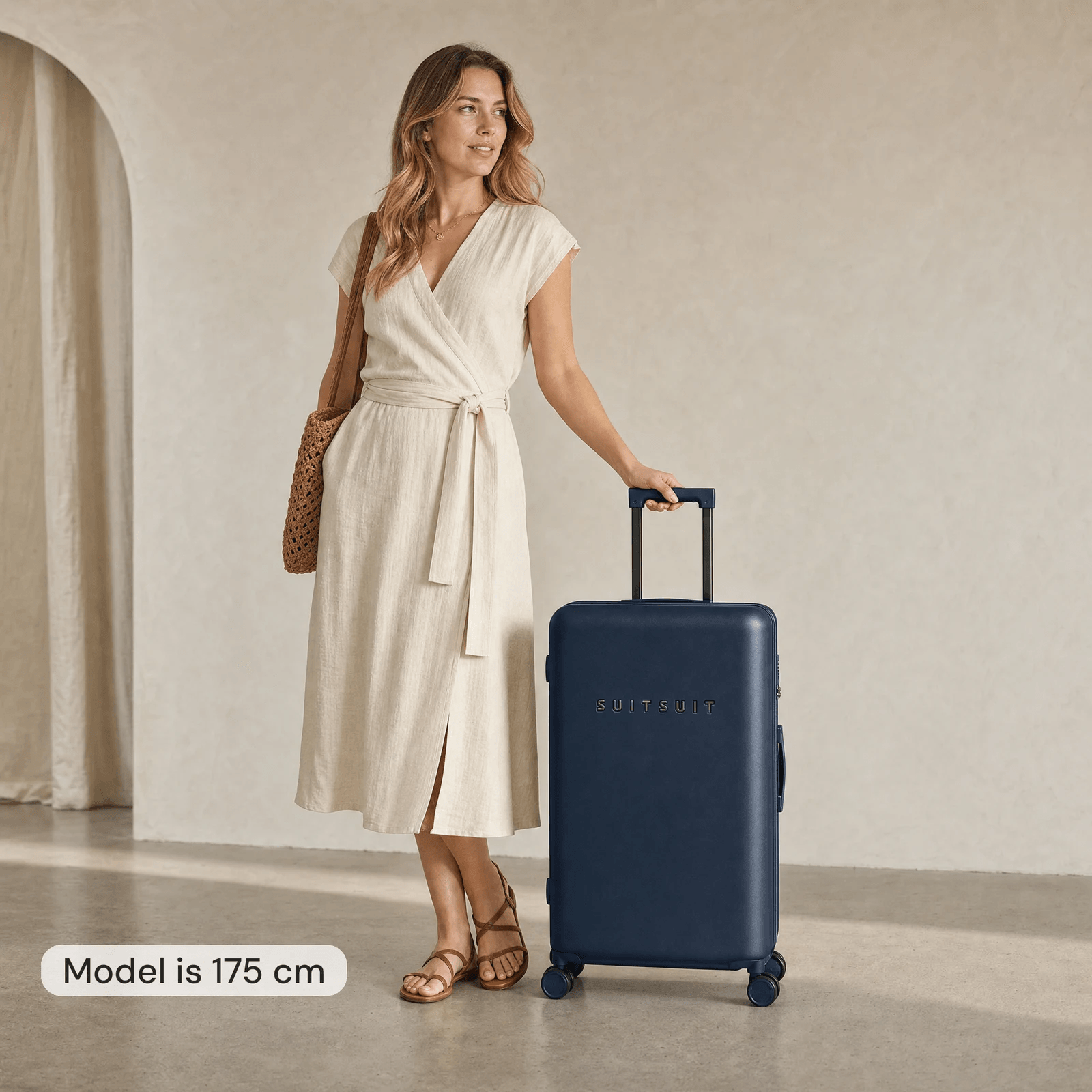 Vrouw van 175 cm naast een donkerblauwe Suitsuit-koffer van 76 cm